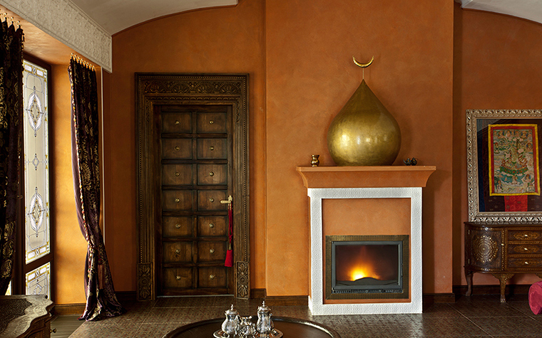 <p>Автор проекта: Pfayfer & Fradina Interior Design</p>
<p>Гостиная, оформленная в восточном стиле, в качестве дополнительного украшения получила оригинальную композицию с фальш-камином. Для декоративного камина был создан традиционный портал, а на каминной полке разместился арт-объект в виде купола с полумесяцем. Золотой купол и искусственный огонь на фоне оранжевых стен смотрятся особенно эффектно!</p>