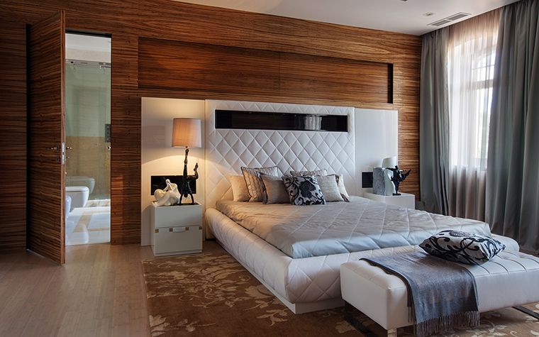 <p>Автор проекта:   Mill-Studio</p>
<p>В этой спальне к белой мебели подобрали ярко-коричневый фон. Это сделали с помощью настенной панели из тонированного дерева и охристого ковра. </p>