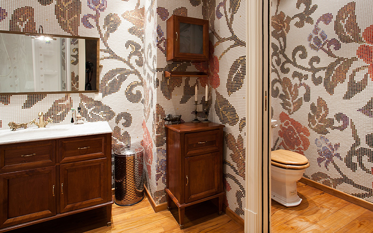 <p>Автор проекта: Юрий Зубенко</p>
<p>Все стены ванной комнаты и туалета украшены пышными мозаичными узорами.  На их фоне неплохо смотрится  деревянная мебель в стиле ретро. </p>
